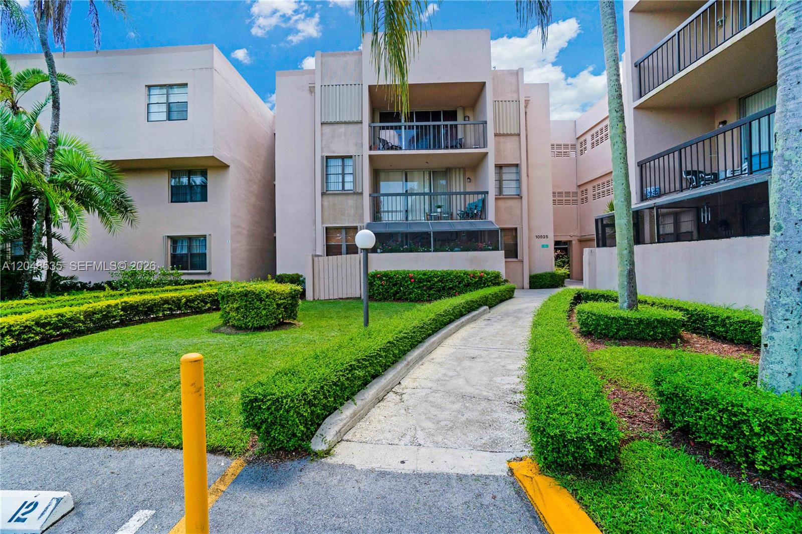 A multi-story apartment building features balconies, a concrete walkway, and manicured hedges on a lawn — 10525 SW 112th Ave # 309, Miami FL 33176, MIAMI, FL
