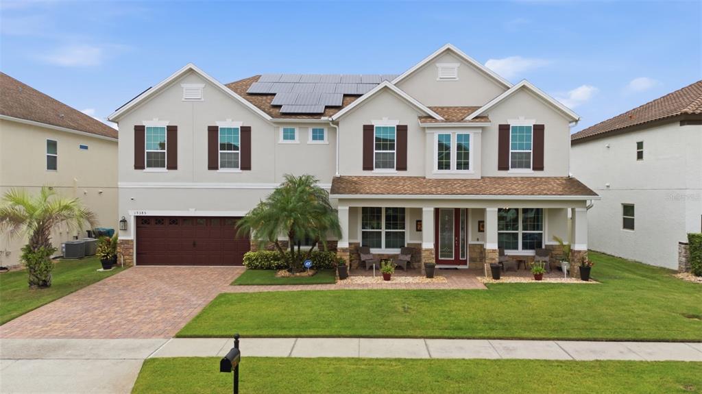 A two-story suburban house with a brown garage, solar panels, and a front porch — 19385 PUMMELO DRIVE, ORLANDO, FL
