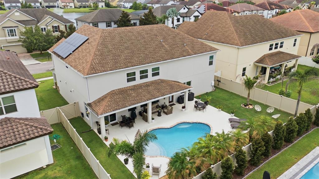 An aerial view shows a two-story house with a backyard pool, patio, and solar panels — 19385 PUMMELO DRIVE, ORLANDO, FL