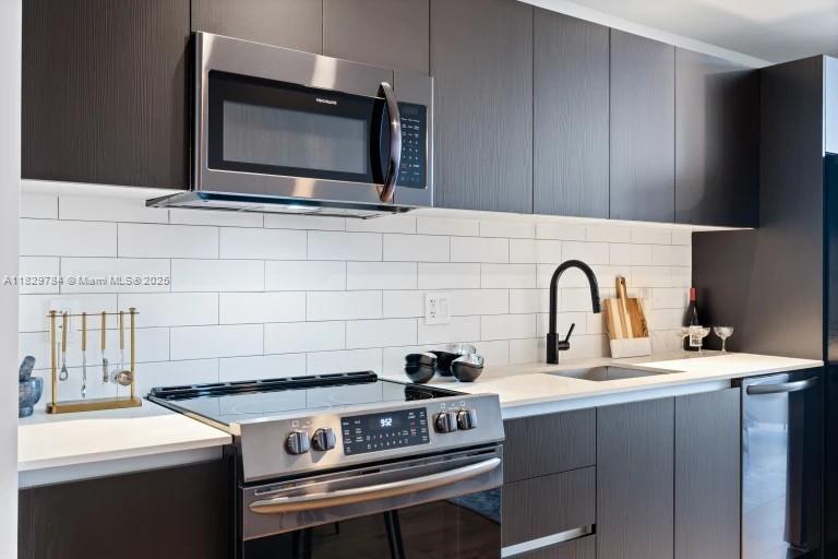 A modern kitchen features dark wood cabinetry, stainless steel appliances, and a white subway tile backsplash — 398 NE 5th St # 4207, Miami FL 33132, MIAMI, FL