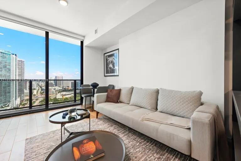 A modern living room features a light-colored sofa, two round coffee tables, and floor-to-ceiling windows — 398 NE 5th St # 4207, Miami FL 33132, MIAMI, FL