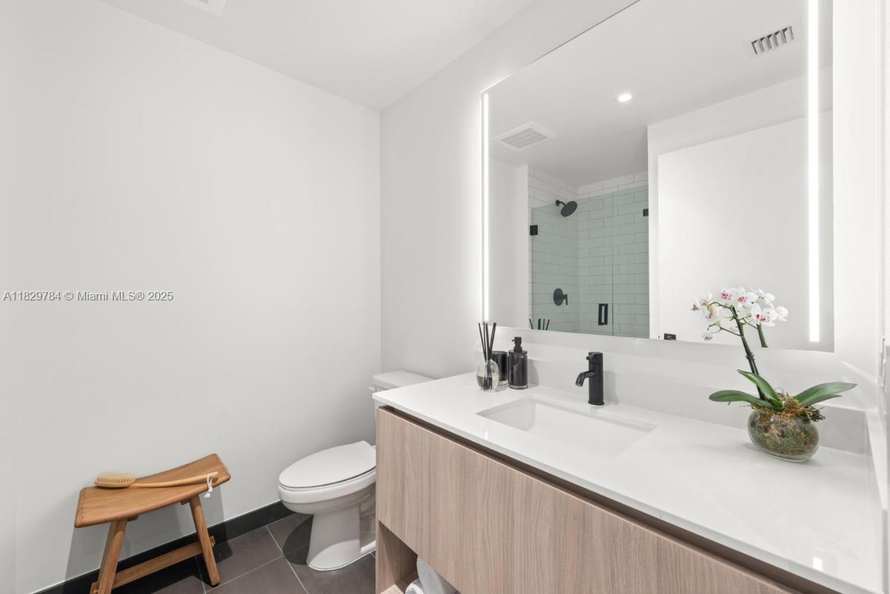 This modern bathroom features a floating wood vanity, white countertop, and a large backlit mirror — 398 NE 5th St # 4207, Miami FL 33132, MIAMI, FL