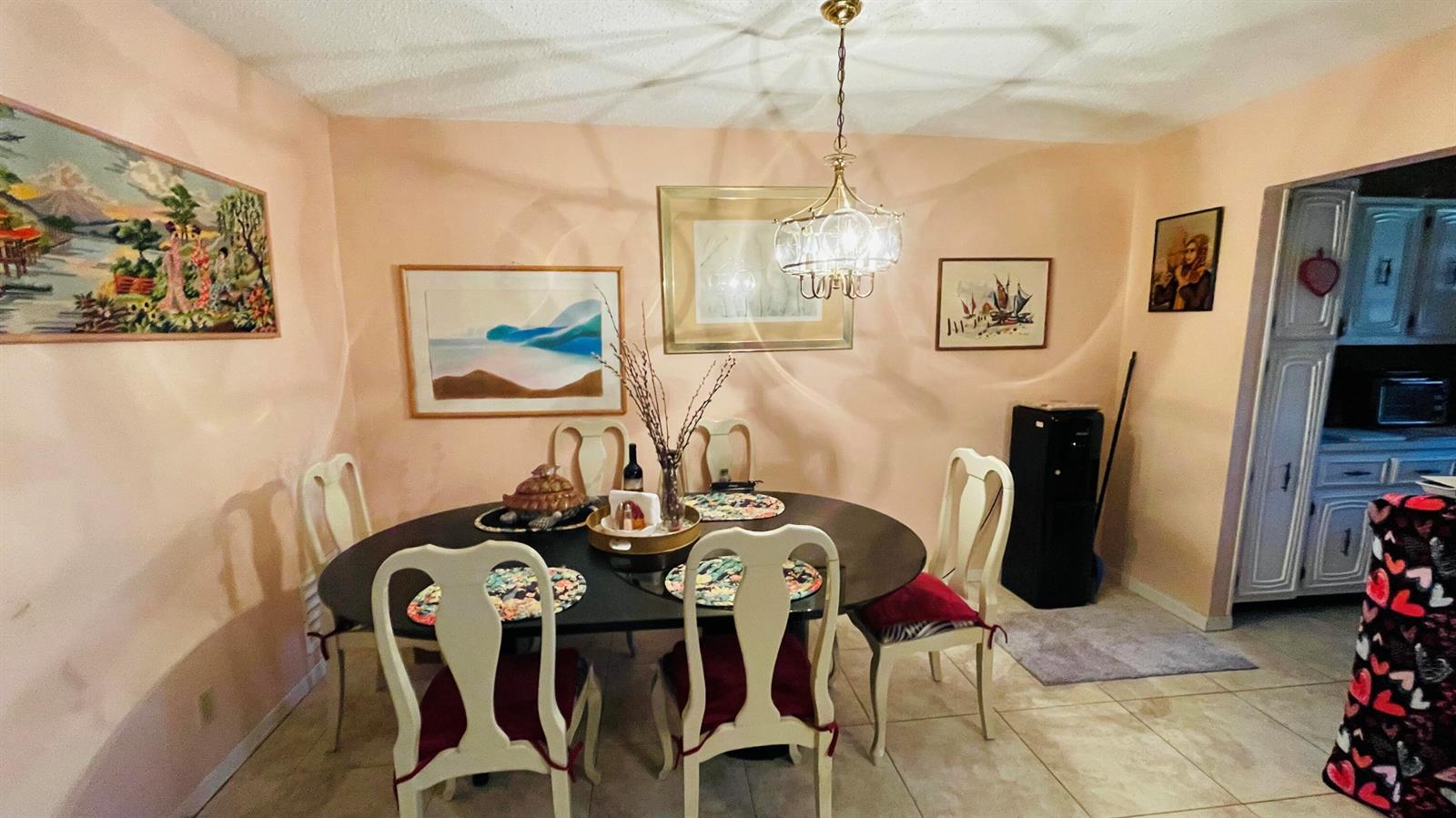 A dining room features a dark oval table, four chairs, and several framed wall artworks — 910 South Drive # B, Delray Beach FL 33445, DELRAY BEACH, FL