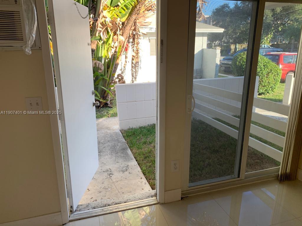 An interior view shows a tiled room with an open door and sliding glass doors — 1511 NE 117th St # 2, Miami FL 33161, MIAMI, FL