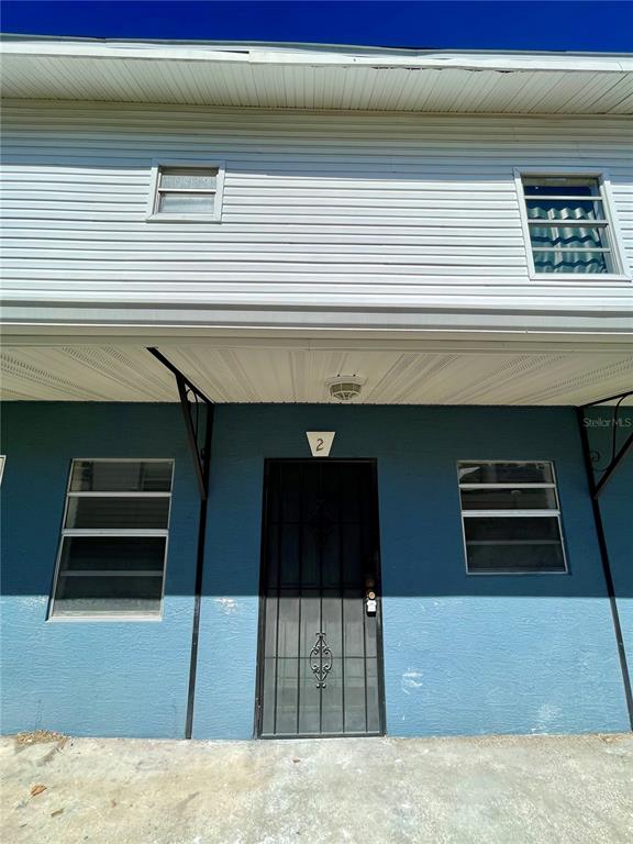 The exterior of a two-story building features blue stucco, white horizontal siding, and a security door — 2916 NORTH 16TH STREET UNIT 2, TAMPA, FL