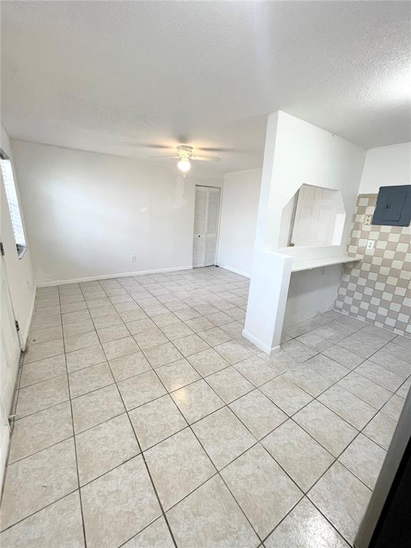 An open-concept room features light-colored tile flooring, a ceiling fan, and a kitchen pass-through window — 2916 NORTH 16TH STREET UNIT 2, TAMPA, FL