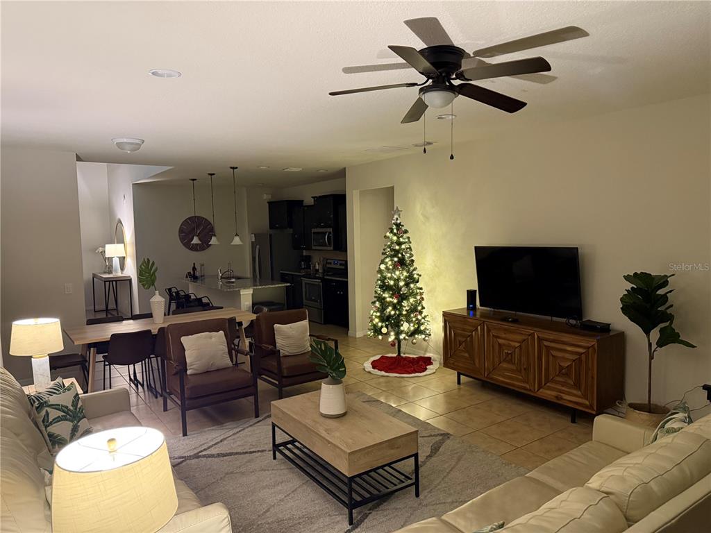 An open-concept living and dining area features tile flooring, a ceiling fan, and a Christmas tree — 1921 NICE COURT, KISSIMMEE, FL