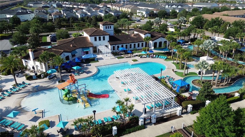 An aerial view shows a community swimming pool complex with a water slide and pergola — 1921 NICE COURT, KISSIMMEE, FL