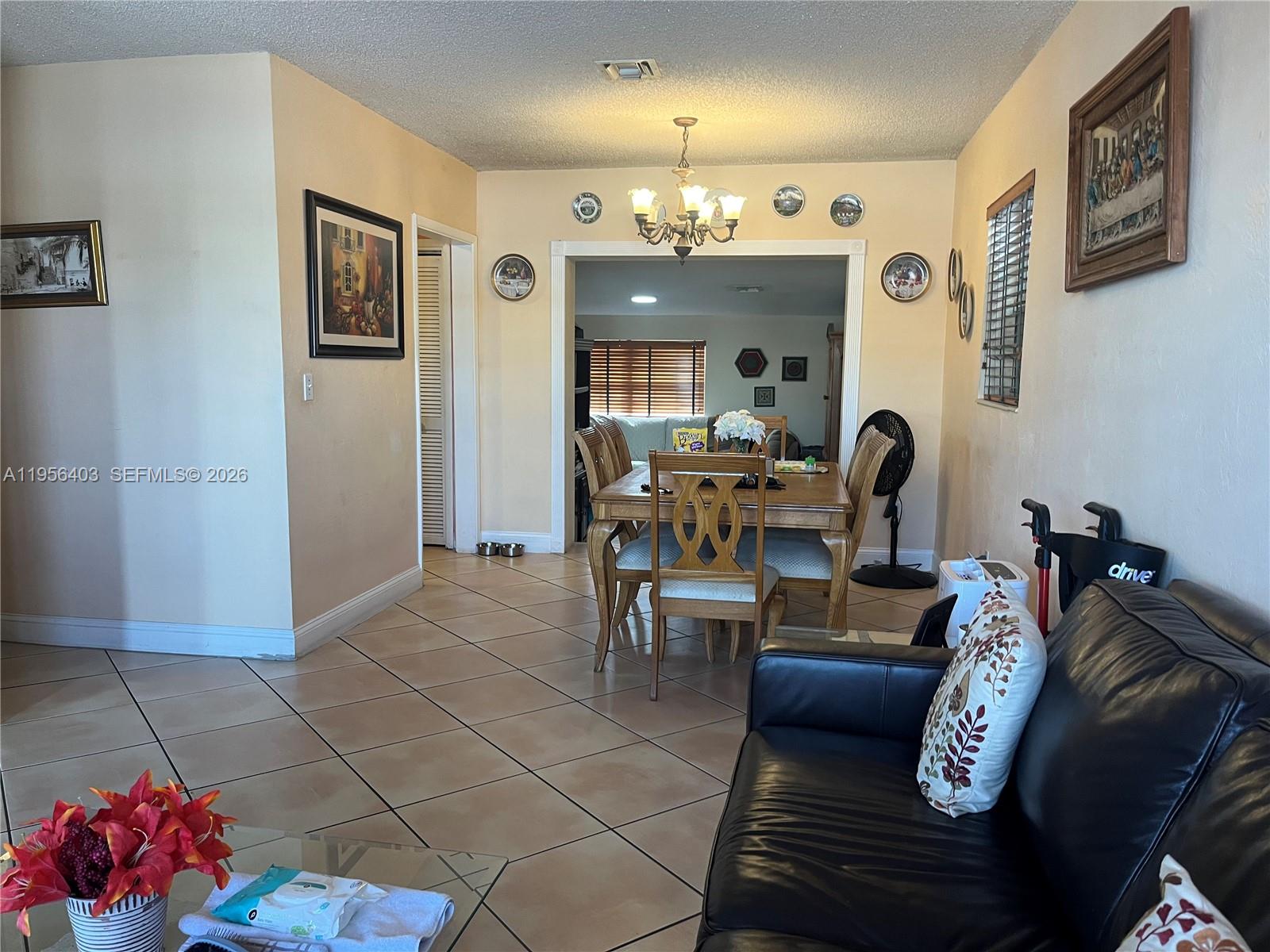 A dining room with a wooden table and chairs sits adjacent to a living area — 9026 SW 34 ST, Miami FL 33165, MIAMI, FL