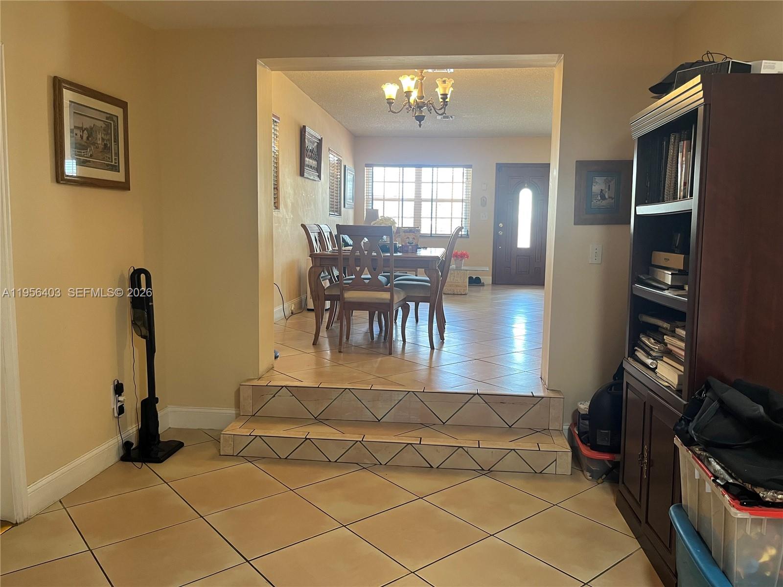 A dining area with a chandelier is elevated by two steps above a tiled room — 9026 SW 34 ST, Miami FL 33165, MIAMI, FL