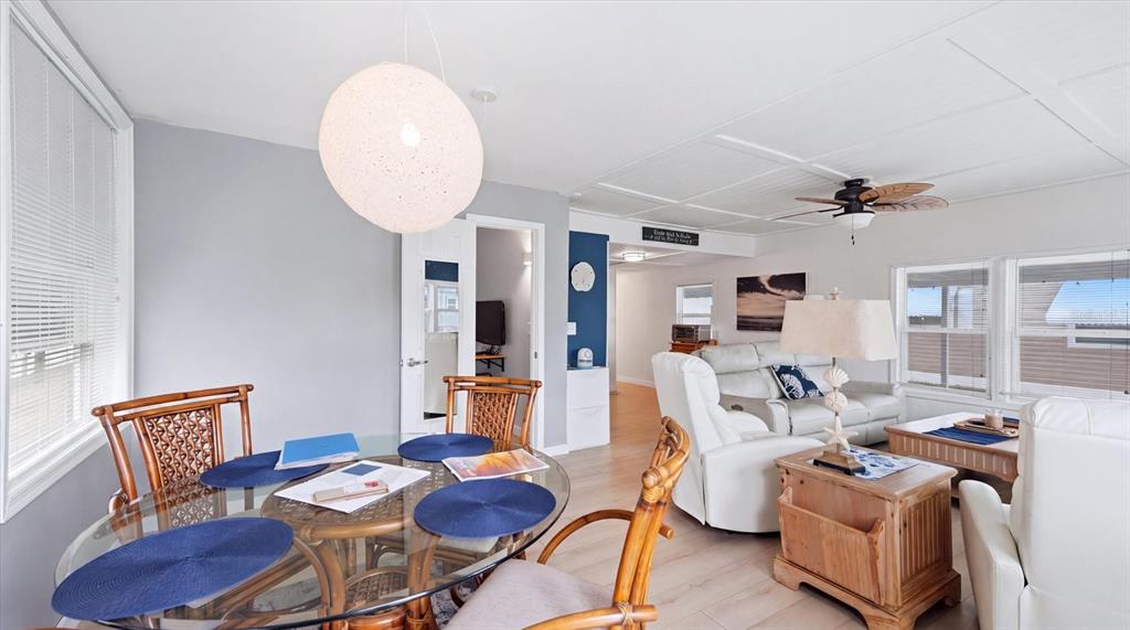 A dining area with a glass table and rattan chairs opens into a living room — 4908 5TH A STREET E, BRADENTON, FL