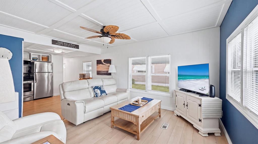 A living room features white walls, a wood-look floor, a white sofa, and a television — 4908 5TH A STREET E, BRADENTON, FL