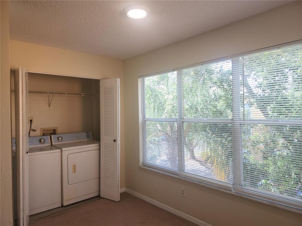 A laundry room features a washer and dryer in a closet, carpet, and large windows — 4518 COMMANDER DRIVE UNIT 1934, ORLANDO, FL