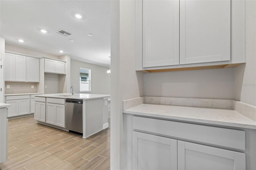 A kitchen with white cabinets, quartz countertops, and light wood-look tile flooring — 19451 FOREST GARDEN COURT, BROOKSVILLE, FL