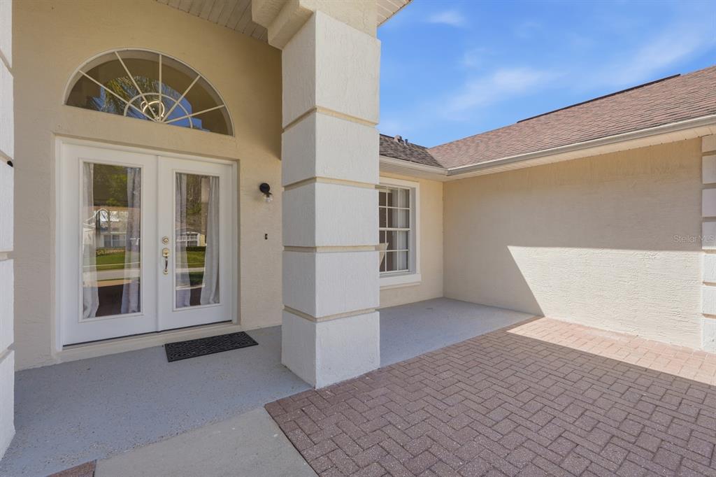 A paved entryway leads to a white double door with an arched transom window — 23 OLD SUNBEAM DRIVE, SOUTH DAYTONA, FL