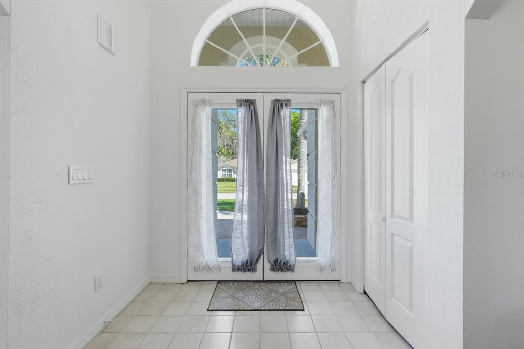 An entryway features white tile floors, double glass doors with curtains, and an arched window — 23 OLD SUNBEAM DRIVE, SOUTH DAYTONA, FL