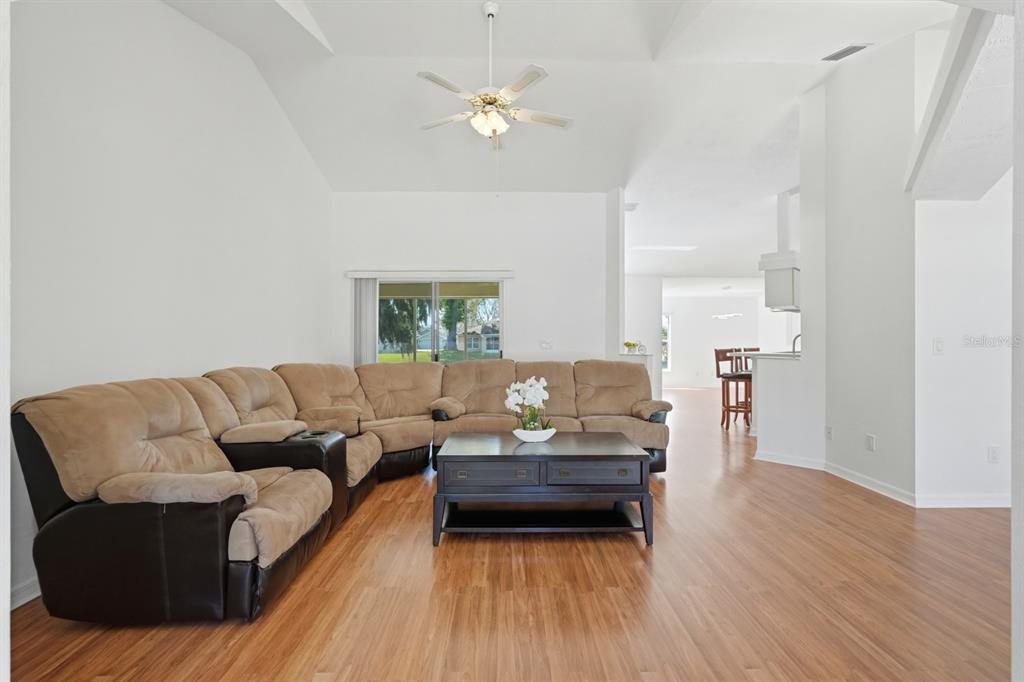 A living room with a large sectional sofa, coffee table, and wood-look flooring — 23 OLD SUNBEAM DRIVE, SOUTH DAYTONA, FL