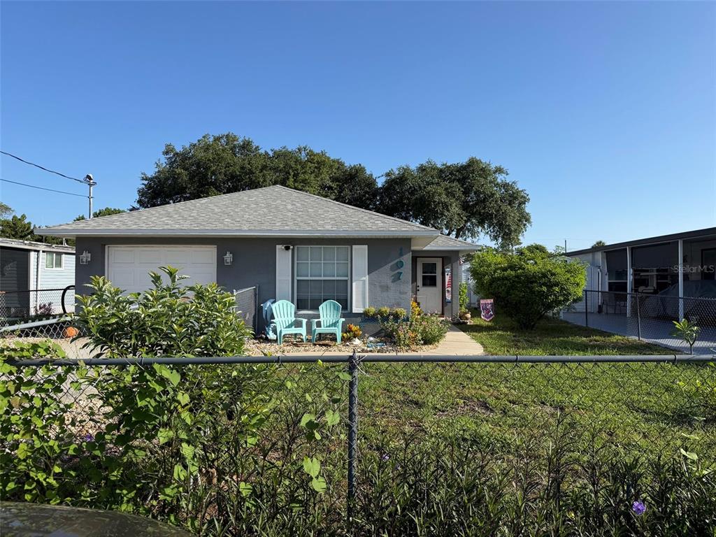 A single-story gray house with a garage and two turquoise chairs sits behind a fence — 107 DOUGLAS STREET, EDGEWATER, FL