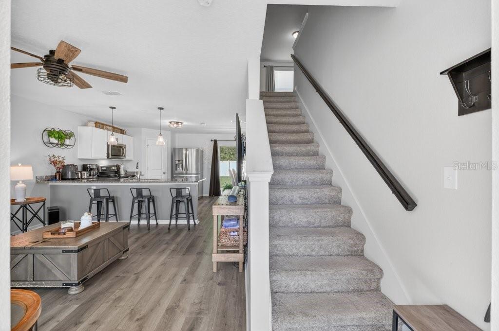A view of a living room with wood-look flooring, a kitchen island, and carpeted stairs — 60 PINE CREST LANE, PALM COAST, FL
