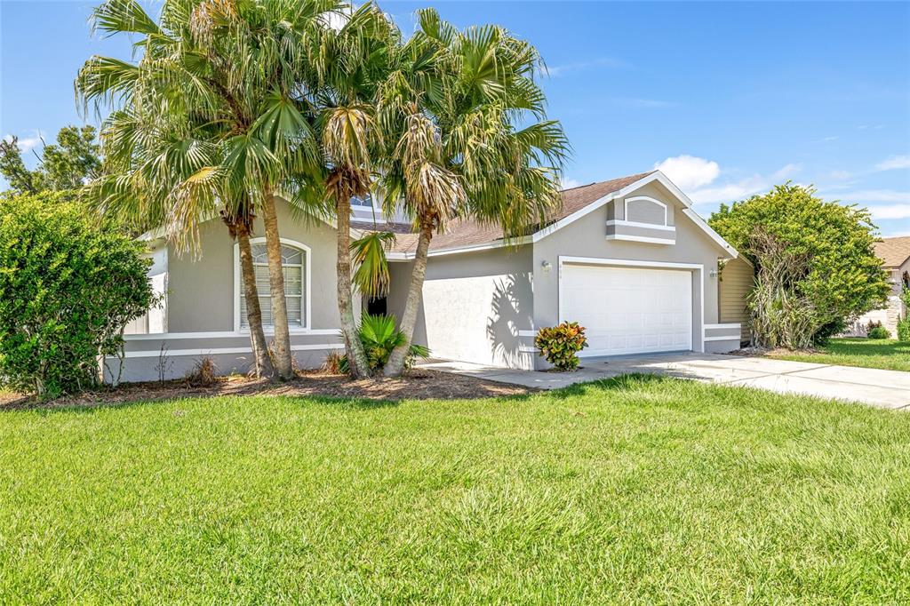 A single-story house with a white garage, gray exterior, and palm trees in the front yard — 404 EMERALD COVE LOOP, LAKELAND, FL