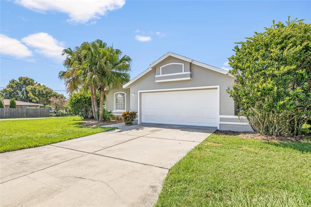A single-story house with a white garage door, a concrete driveway, and palm trees — 404 EMERALD COVE LOOP, LAKELAND, FL
