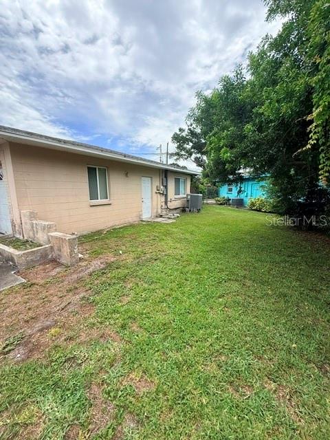 The exterior of a tan, single-story house features a grassy yard and a white door — 830 55TH AVENUE S, ST PETERSBURG, FL