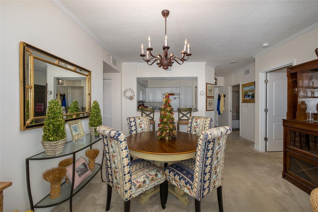 A dining area features a round wooden table, patterned chairs, and a chandelier — 4516 SEAGULL DRIVE UNIT 413, NEW PORT RICHEY, FL