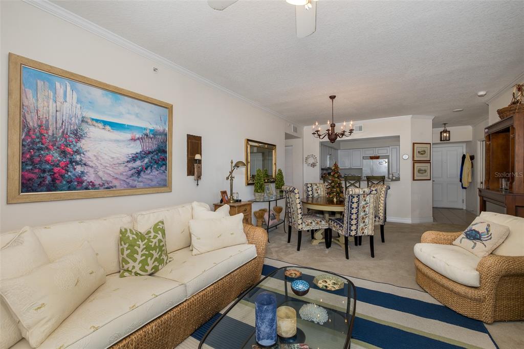A living room and dining area featuring wicker furniture, a striped rug, and coastal decor — 4516 SEAGULL DRIVE UNIT 413, NEW PORT RICHEY, FL