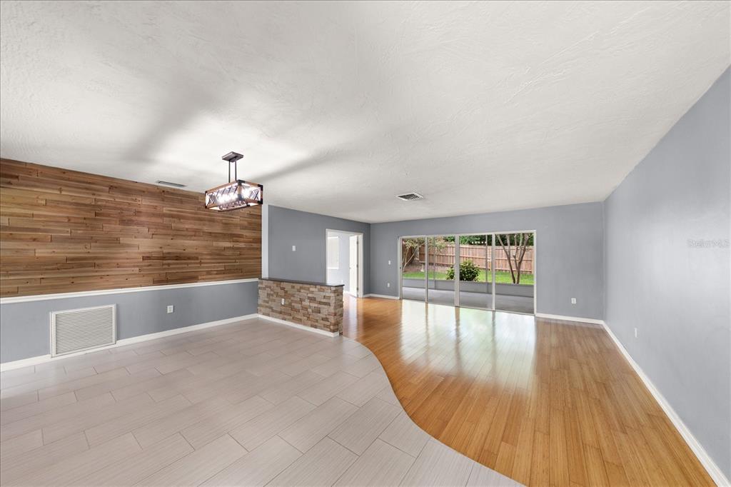 A living area features a wood-paneled accent wall, stone half-wall, tile and wood flooring, and sliding doors — 208 TALLEY DRIVE, PALM HARBOR, FL