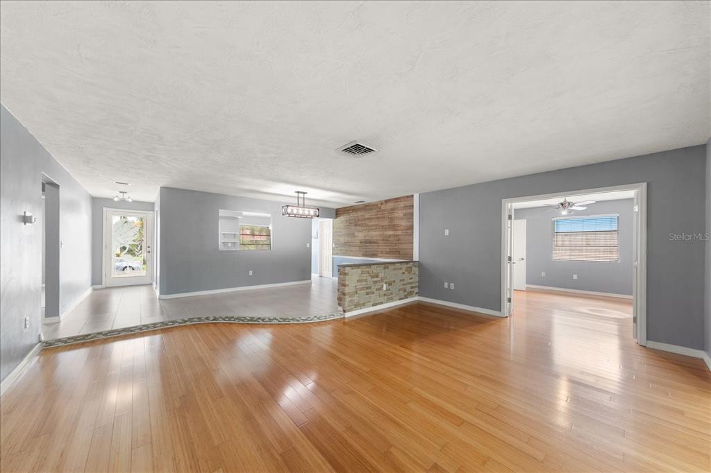 A living room with hardwood floors, gray walls, and a stone-accented half wall — 208 TALLEY DRIVE, PALM HARBOR, FL