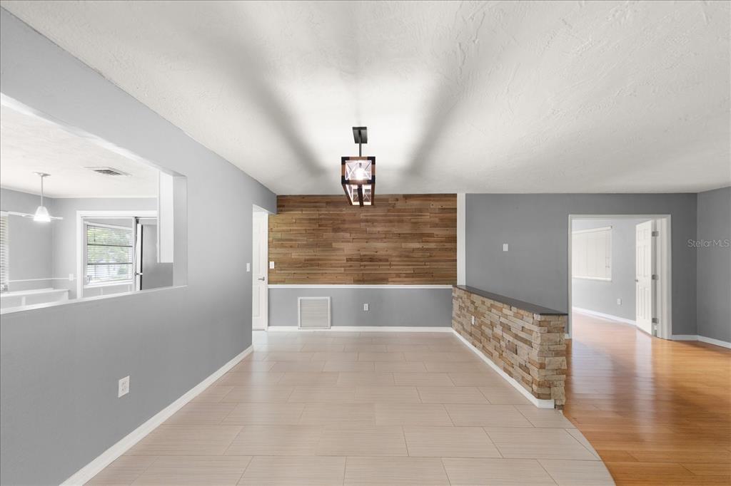 A dining area features light tile flooring, a wood-paneled accent wall, and a stone half-wall — 208 TALLEY DRIVE, PALM HARBOR, FL