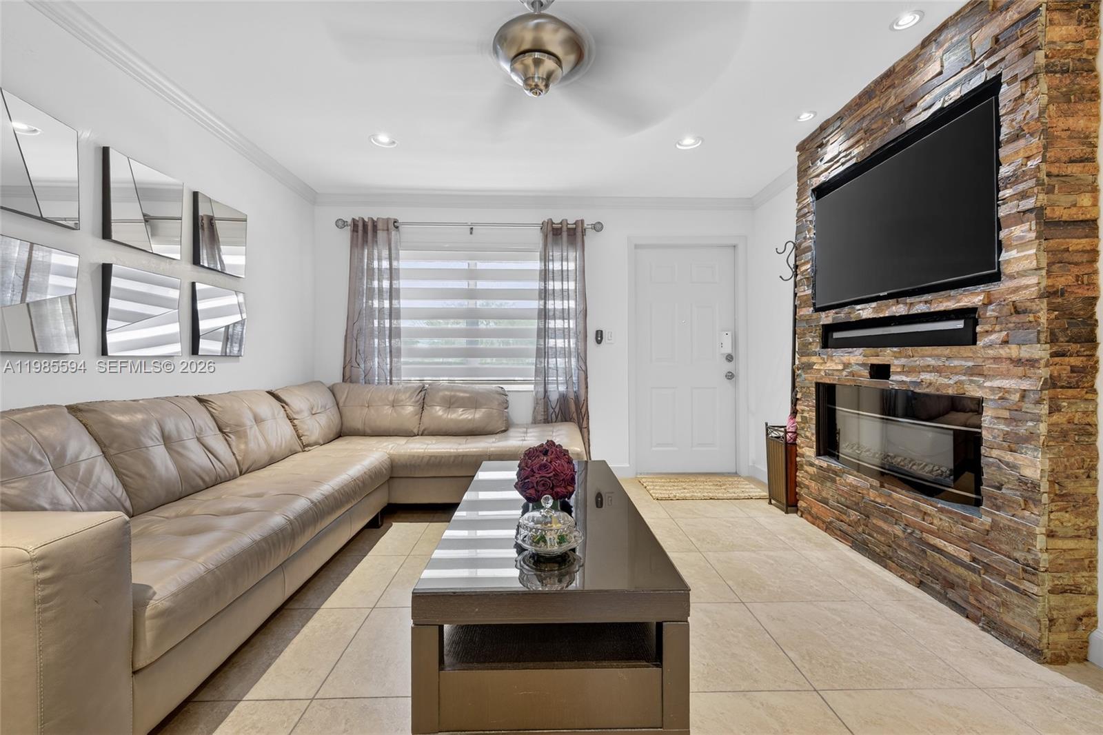 A living room features a beige sectional sofa, a stone fireplace wall, and tile flooring — 3777 NW 78th Ave # 8F, Davie FL 33024, DAVIE, FL