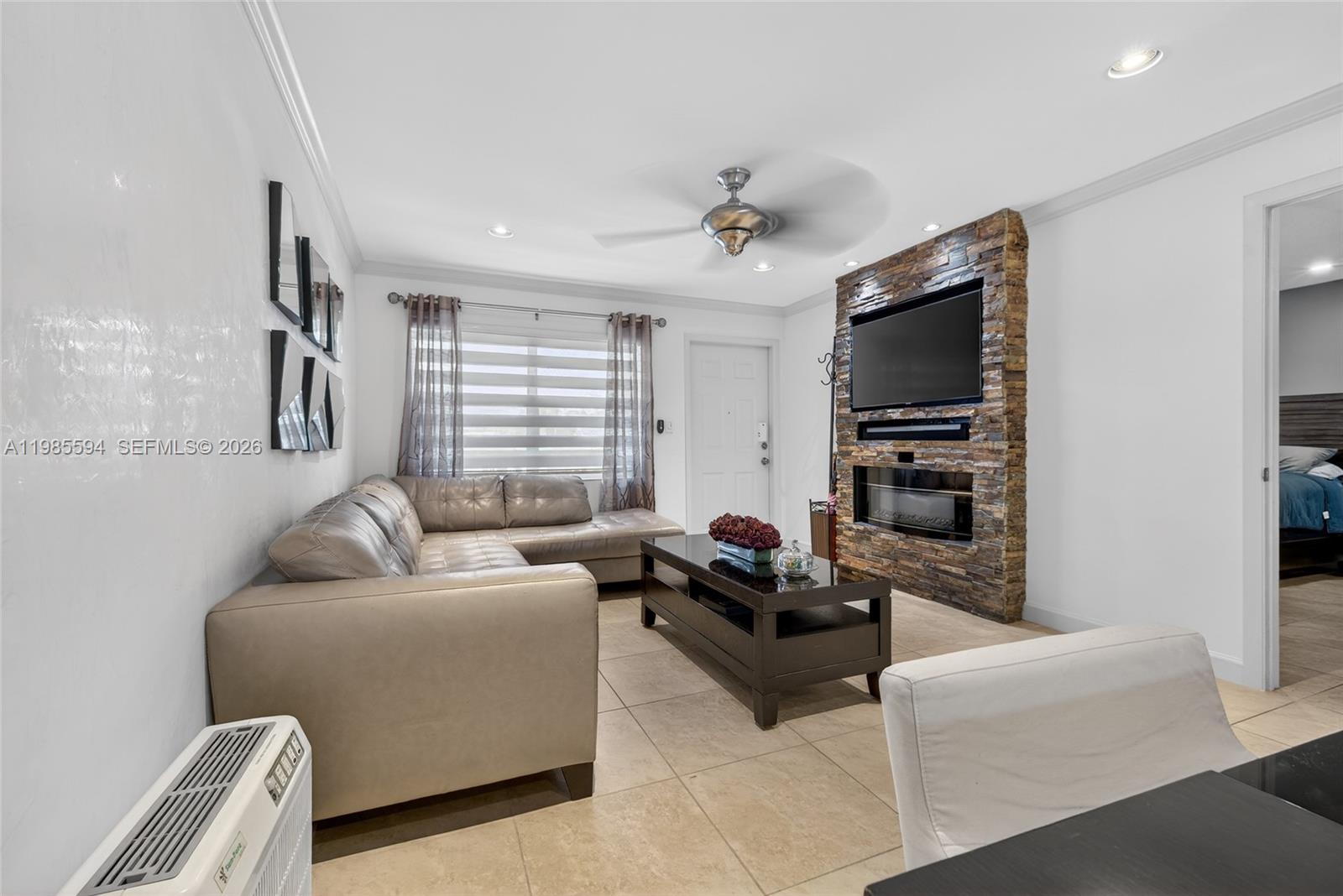 A living room features a stone-accented fireplace wall, a sectional sofa, and tile flooring — 3777 NW 78th Ave # 8F, Davie FL 33024, DAVIE, FL