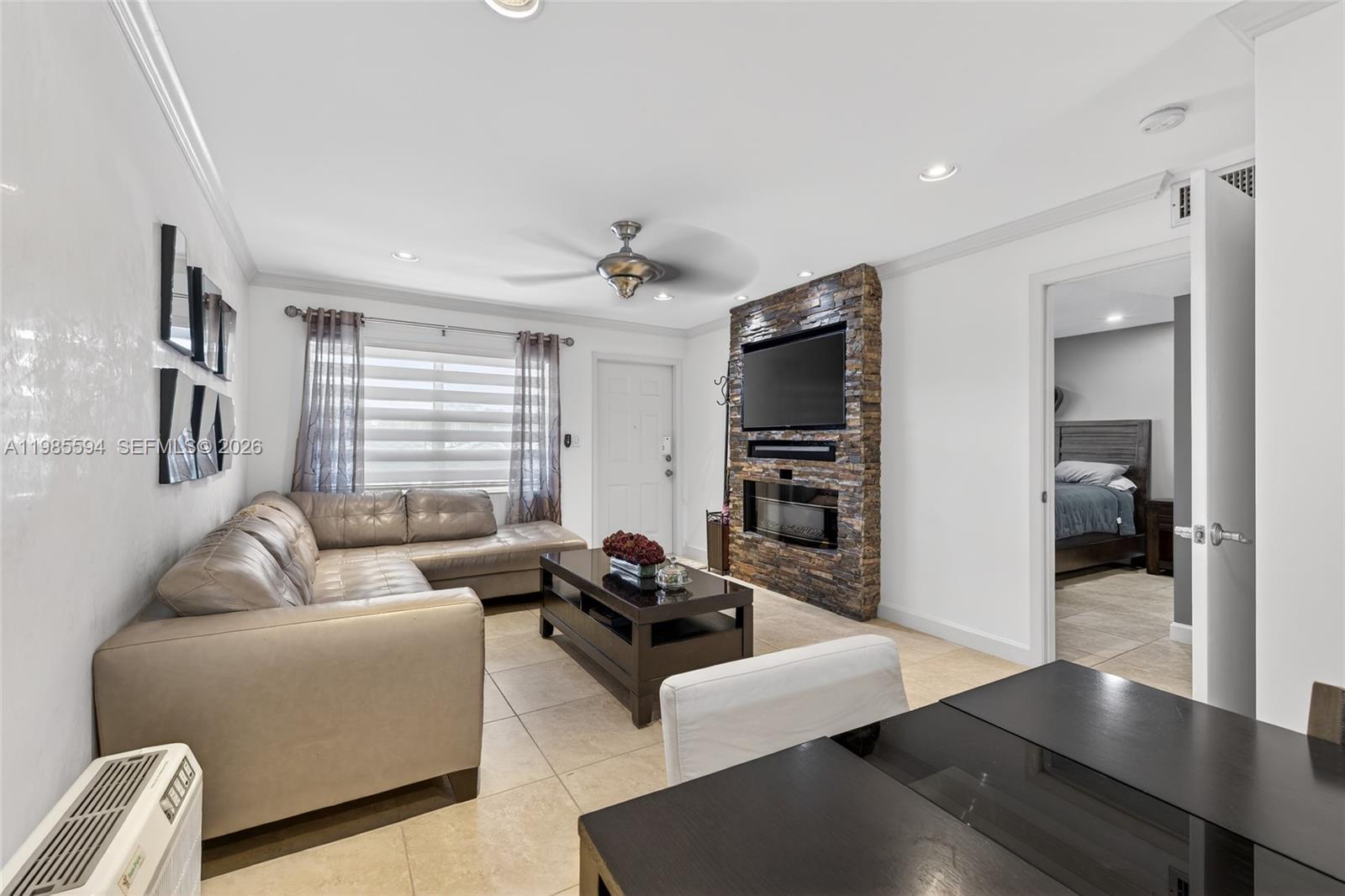 A living room features a stone fireplace, a sectional sofa, and an adjacent bedroom doorway — 3777 NW 78th Ave # 8F, Davie FL 33024, DAVIE, FL