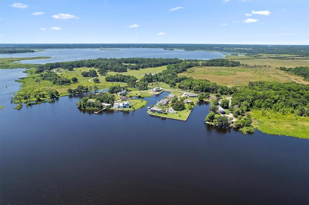 An aerial view shows a green metal building with a patio overlooking a waterfront dock — 3943 NW 219TH STREET ROAD, MICANOPY, FL