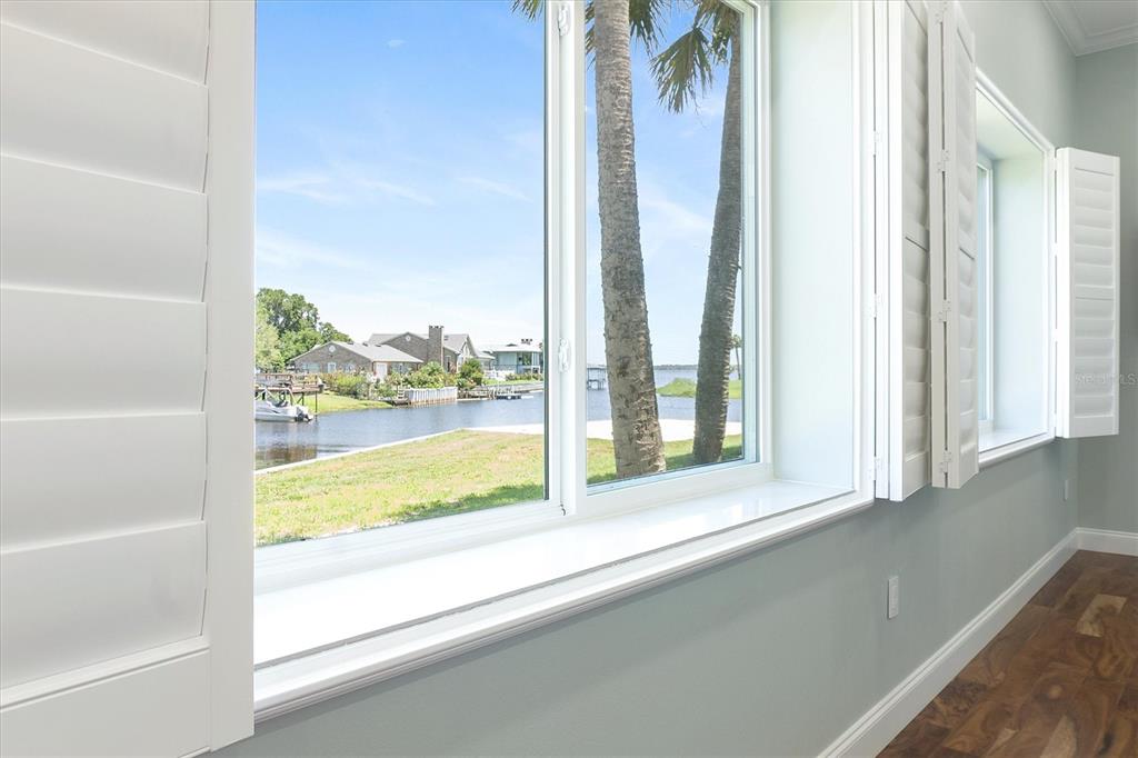 A view of a waterfront canal through large windows with white plantation shutters — 3943 NW 219TH STREET ROAD, MICANOPY, FL
