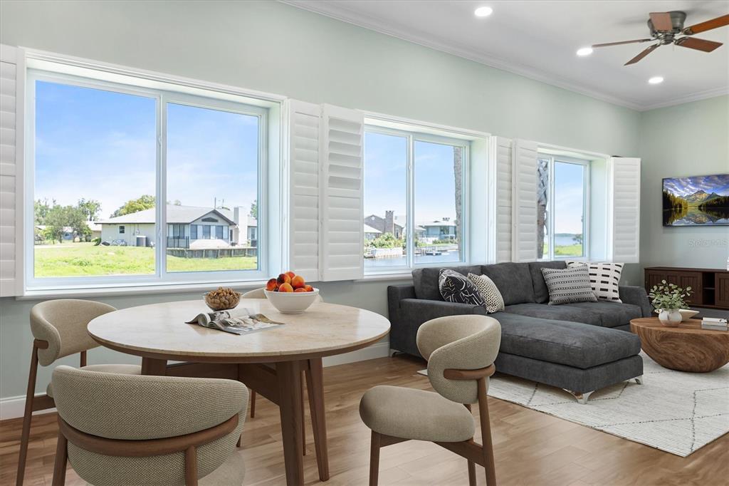 A dining area and living room with large windows, light wood floors, and water views — 3943 NW 219TH STREET ROAD, MICANOPY, FL