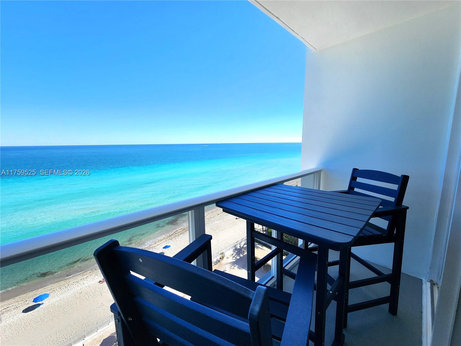 A balcony with a small table and two chairs overlooks a beach and ocean — 3505 S Ocean Dr # 1014, Hollywood FL 33019, HOLLYWOOD, FL