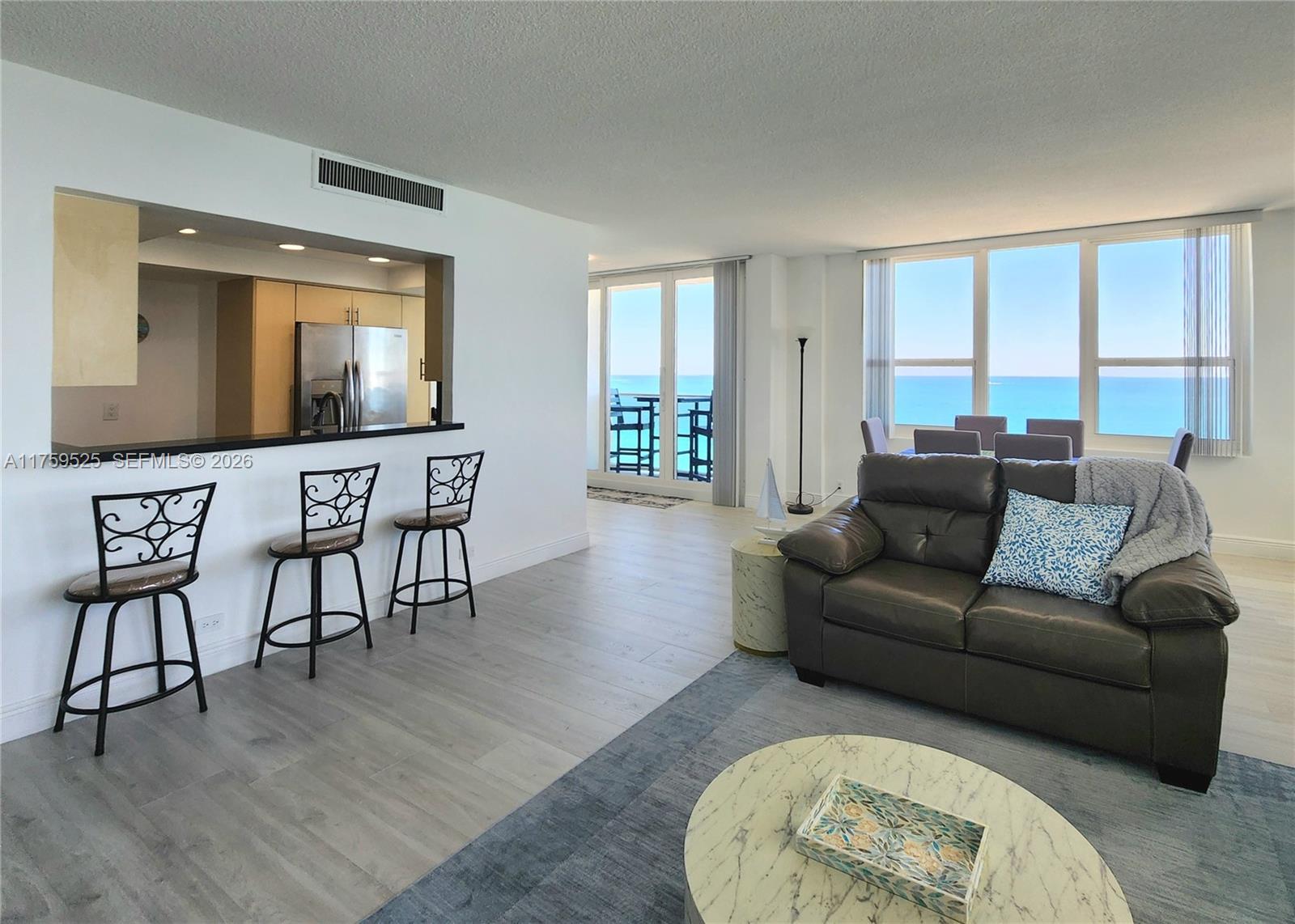 A living room and kitchen area feature light wood floors, a dark sofa, and ocean views — 3505 S Ocean Dr # 1014, Hollywood FL 33019, HOLLYWOOD, FL