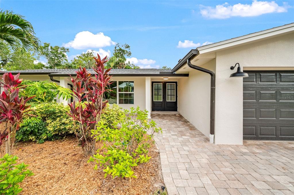A paved walkway leads to the front entrance of a house with a dark garage — 105 BRIARWOOD LANE, COCOA, FL