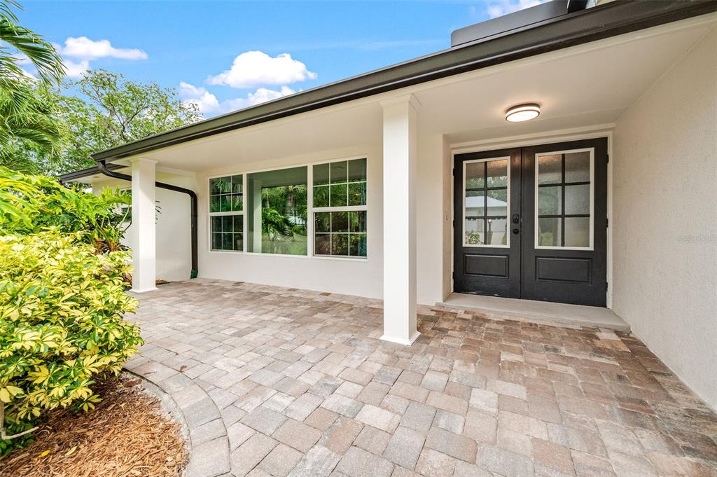 A paved patio leads to a set of black double doors under a covered entryway — 105 BRIARWOOD LANE, COCOA, FL