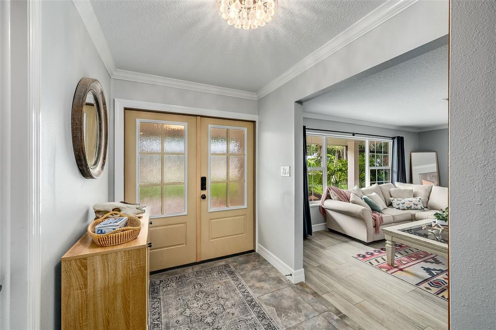 An entryway with a wooden console table leads into a living room with light flooring — 105 BRIARWOOD LANE, COCOA, FL