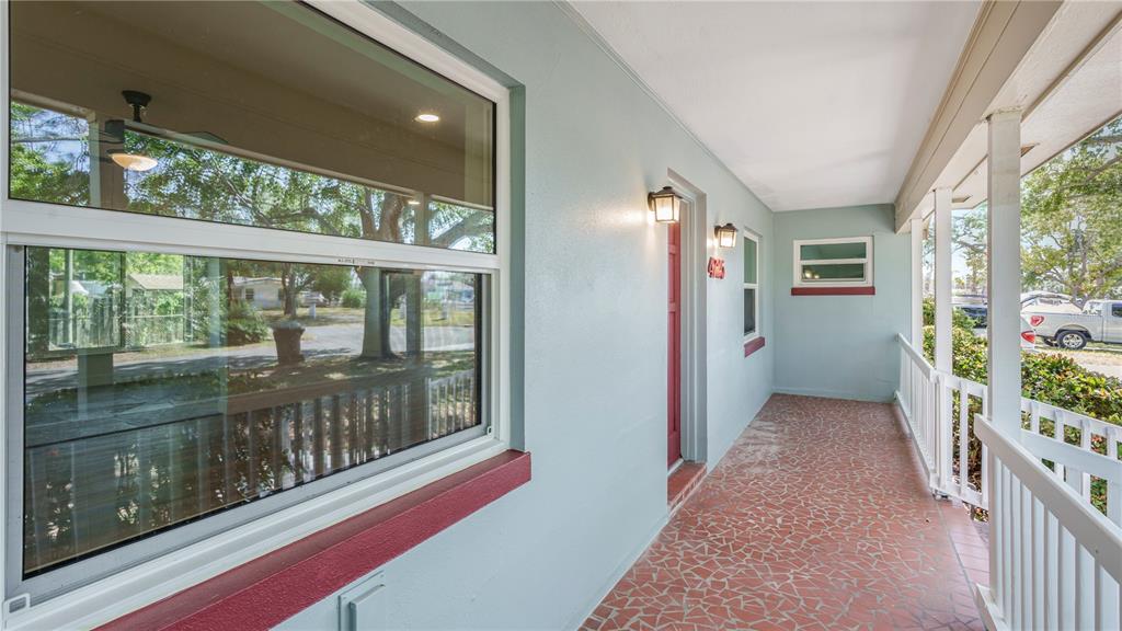 A covered porch with a red tile floor, light blue walls, and a red front door — 4725 DEL RIO WAY S, GULFPORT, FL