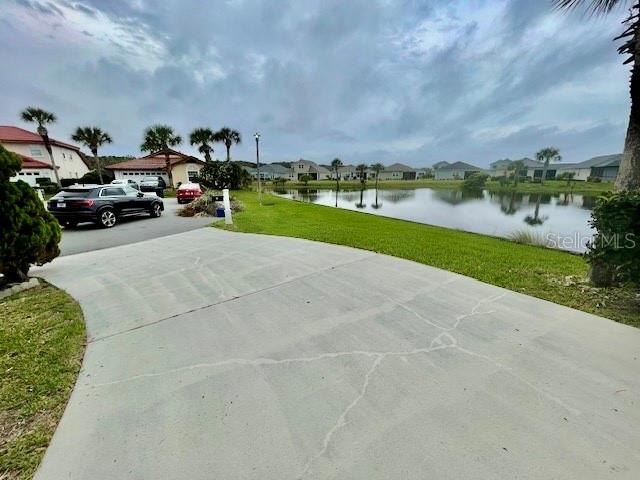 A concrete driveway leads toward a suburban street with houses overlooking a small lake — 30 SAN RAFAEL COURT, PALM COAST, FL