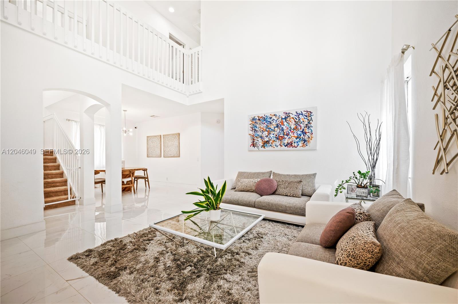 A bright living room features high ceilings, white tile floors, and a glass coffee table — 445 Conservation Dr, Weston FL 33327, WESTON, FL