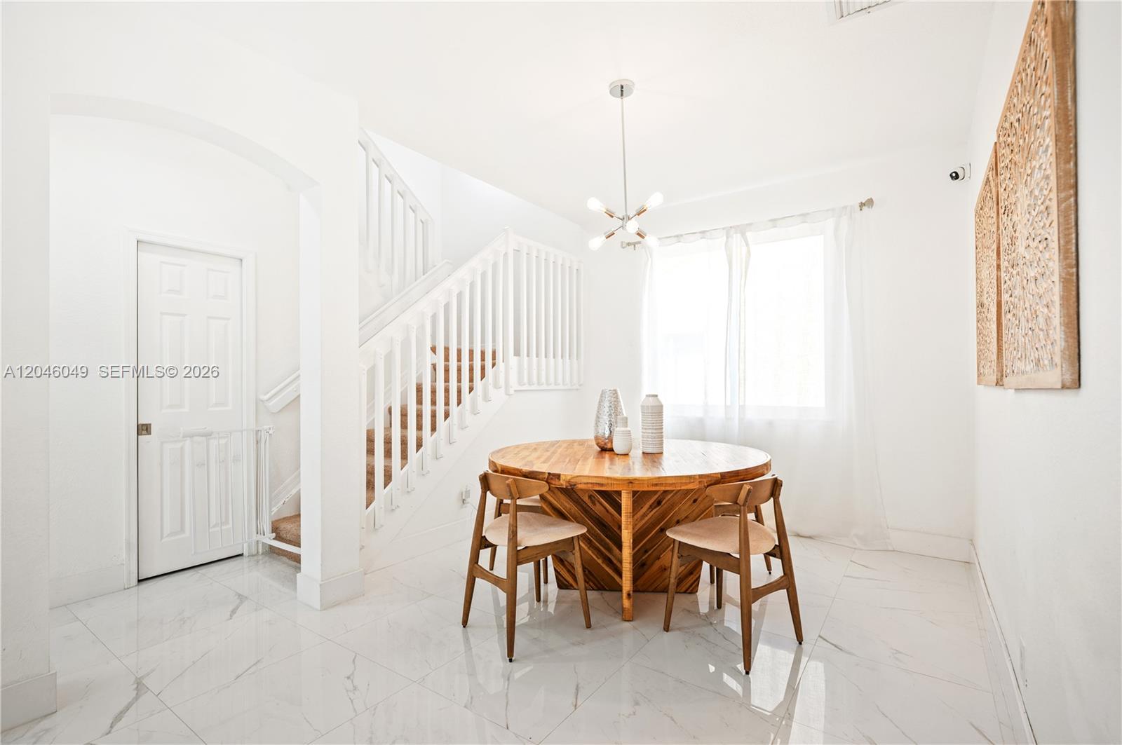 A dining area features a round wooden table, chairs, and a staircase on white tile — 445 Conservation Dr, Weston FL 33327, WESTON, FL