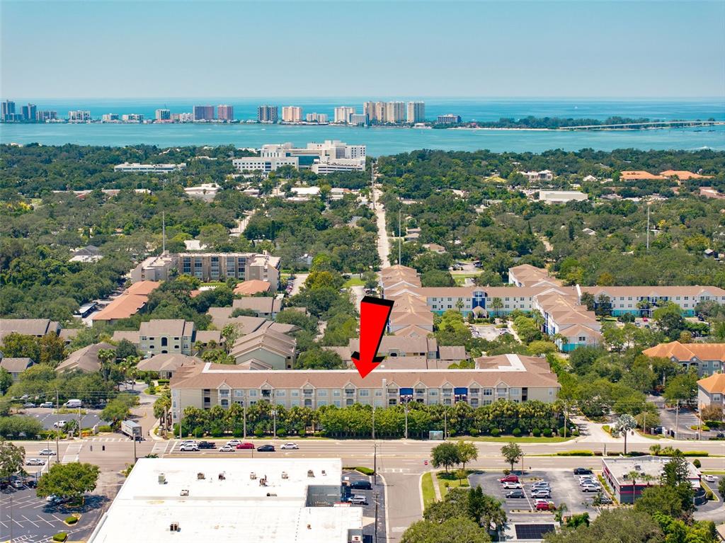 An aerial view shows a multi-story apartment complex with a red arrow pointing toward it — 1216 S MISSOURI AVENUE UNIT 419, CLEARWATER, FL