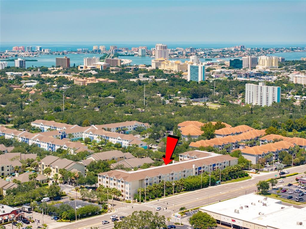 An aerial view shows a multi-story apartment complex with a red arrow pointing toward it — 1216 S MISSOURI AVENUE UNIT 419, CLEARWATER, FL