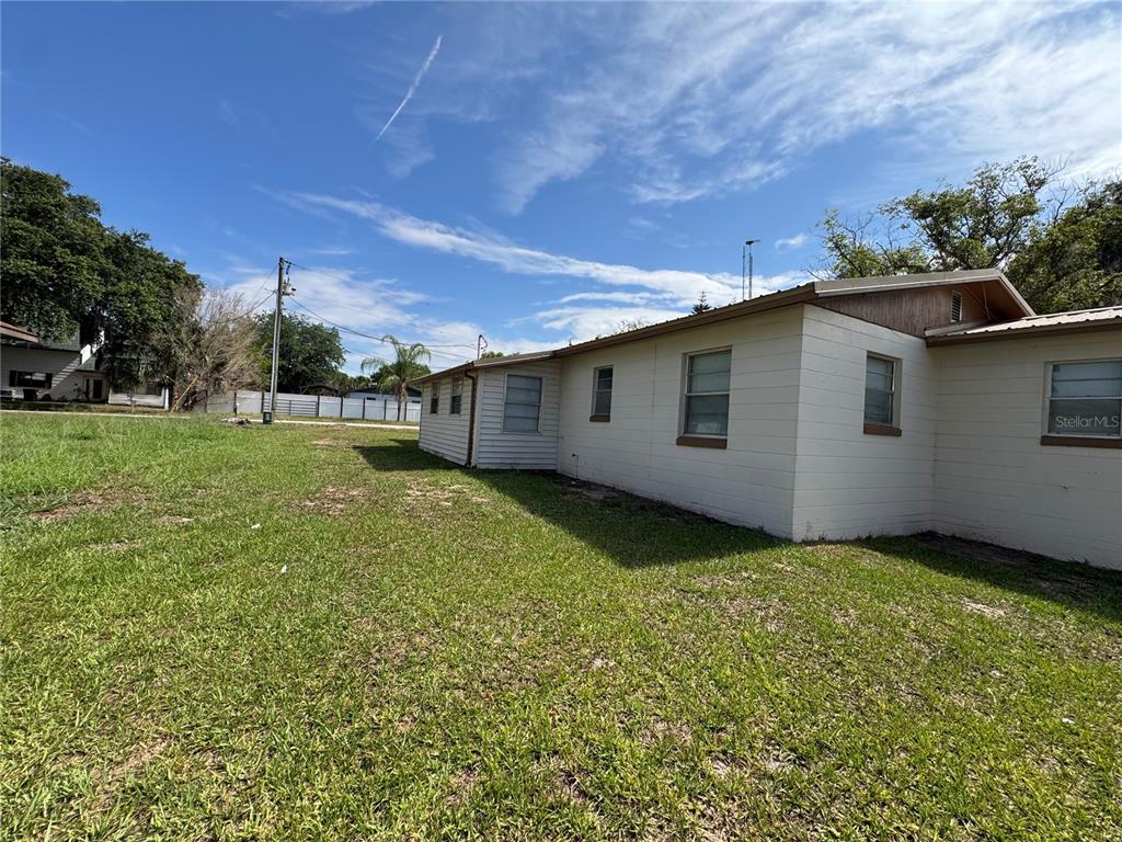 The exterior side view of a light-colored house features block walls and multiple windows — 307 N LAKE REEDY BOULEVARD, FROSTPROOF, FL