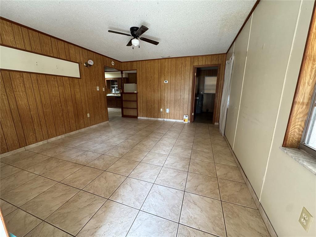 An empty room features wood-paneled walls, tiled flooring, a ceiling fan, and two doorways — 307 N LAKE REEDY BOULEVARD, FROSTPROOF, FL